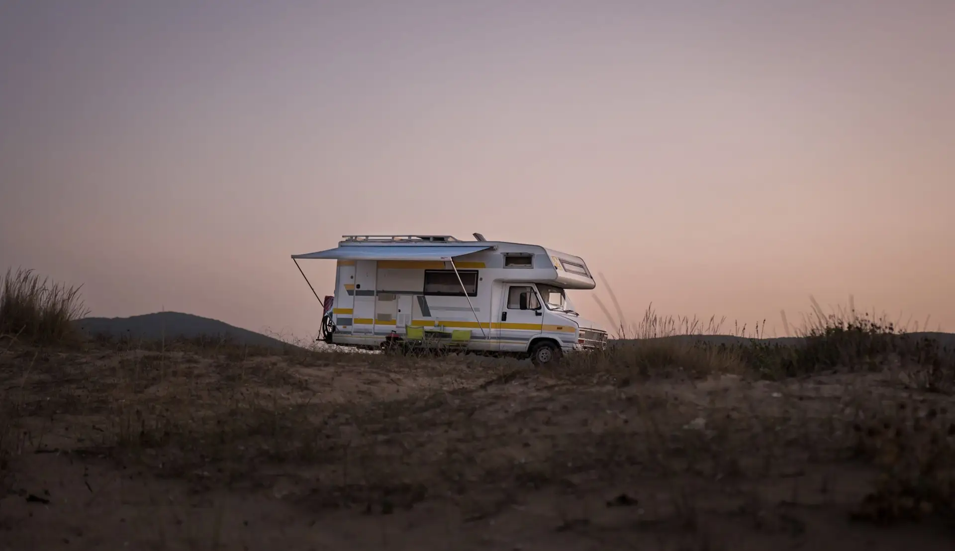 A motorhome parked on high desert ground at dusk
